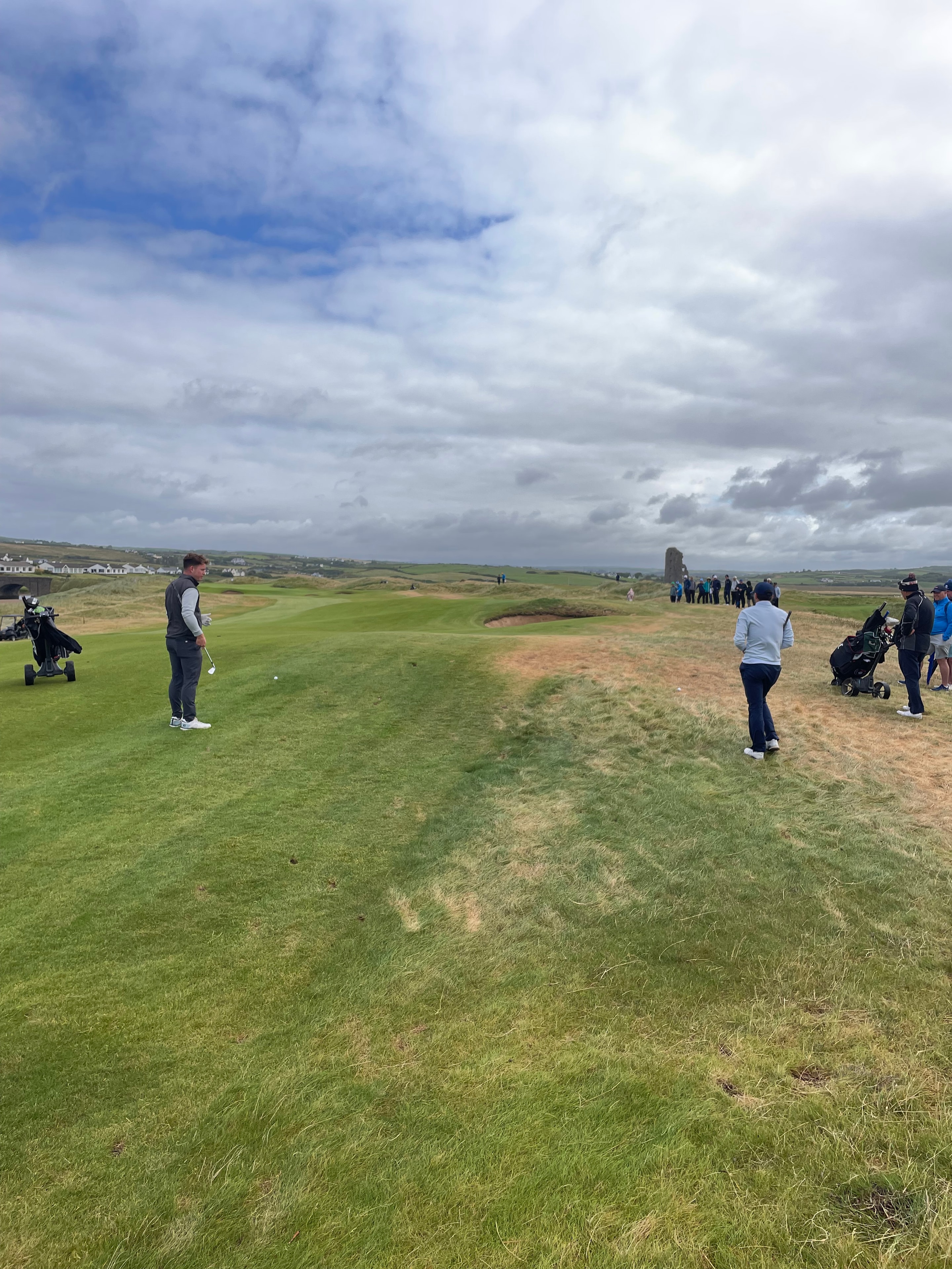 Golfers on a clifftop green at Lahinch with the Atlantic Ocean stretching to the horizon behind them